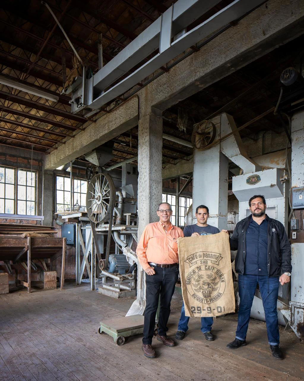 Tres integrantes de la familia en el molino, junto al saco de café de Boquete