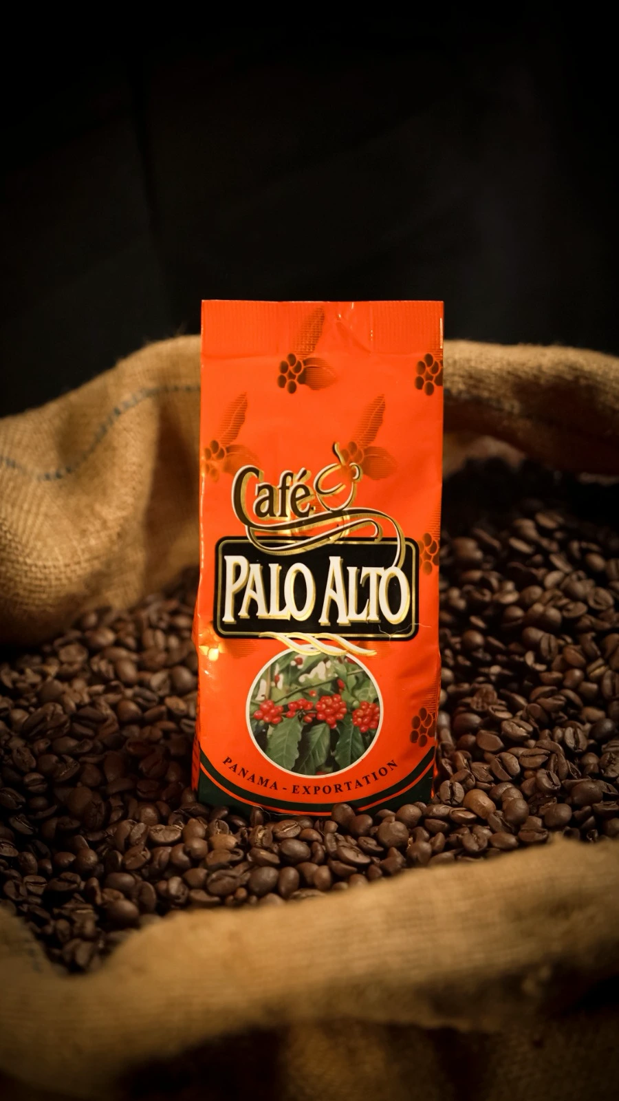 Empaque original naranja de Café Palo Alto sobre granos de café y un saco de fibra natural